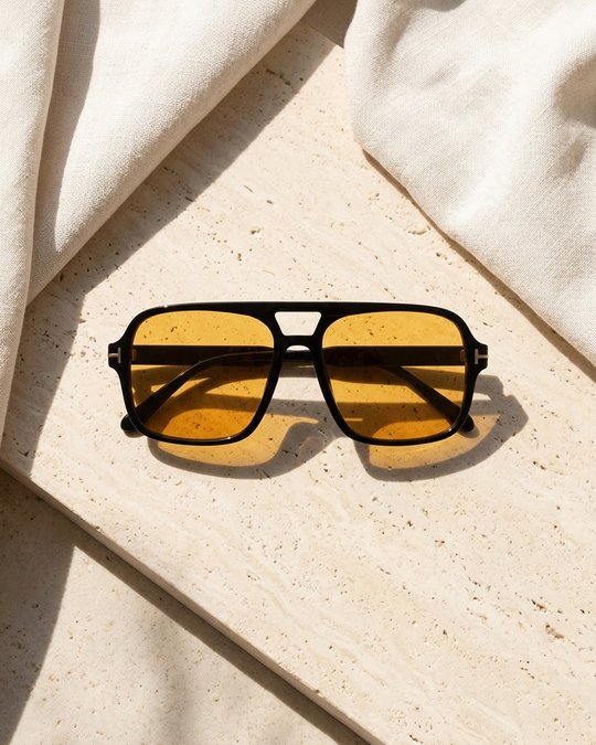 Iris Frames Riviera sunglasses in black frame with blue tinted lenses on travertine stone with white linen